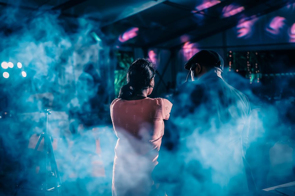 Živopisan prizor noćnog kluba s dvije figure i dramatičnim scenskim svjetlom i dimom